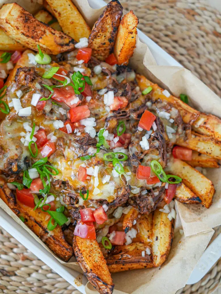 Beef Brisket Loaded Fries, topped with melted cheese, tender beef brisket, and fresh garnishes.