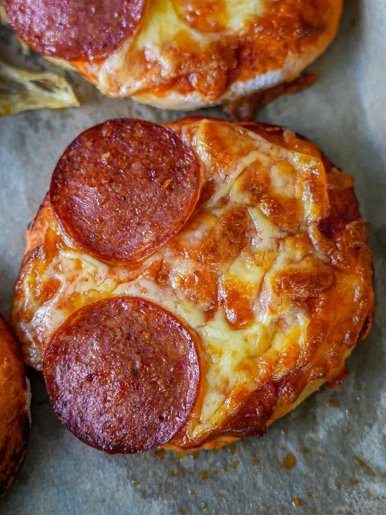 Close-up of mini pizzas, highlighting the crispy dough, rich tomato sauce, and gooey mozzarella with pepperoni slices