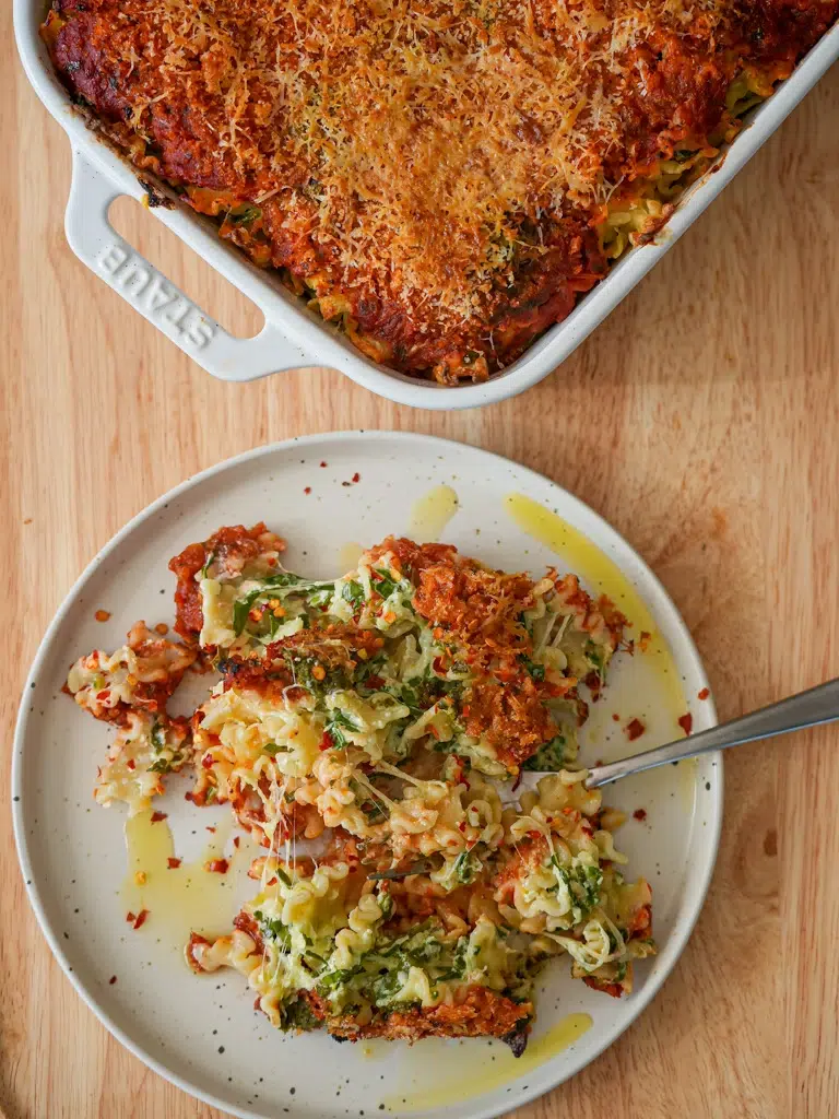 Served on a plate, creamy spinach and cheese pasta bake with a crispy golden layer.